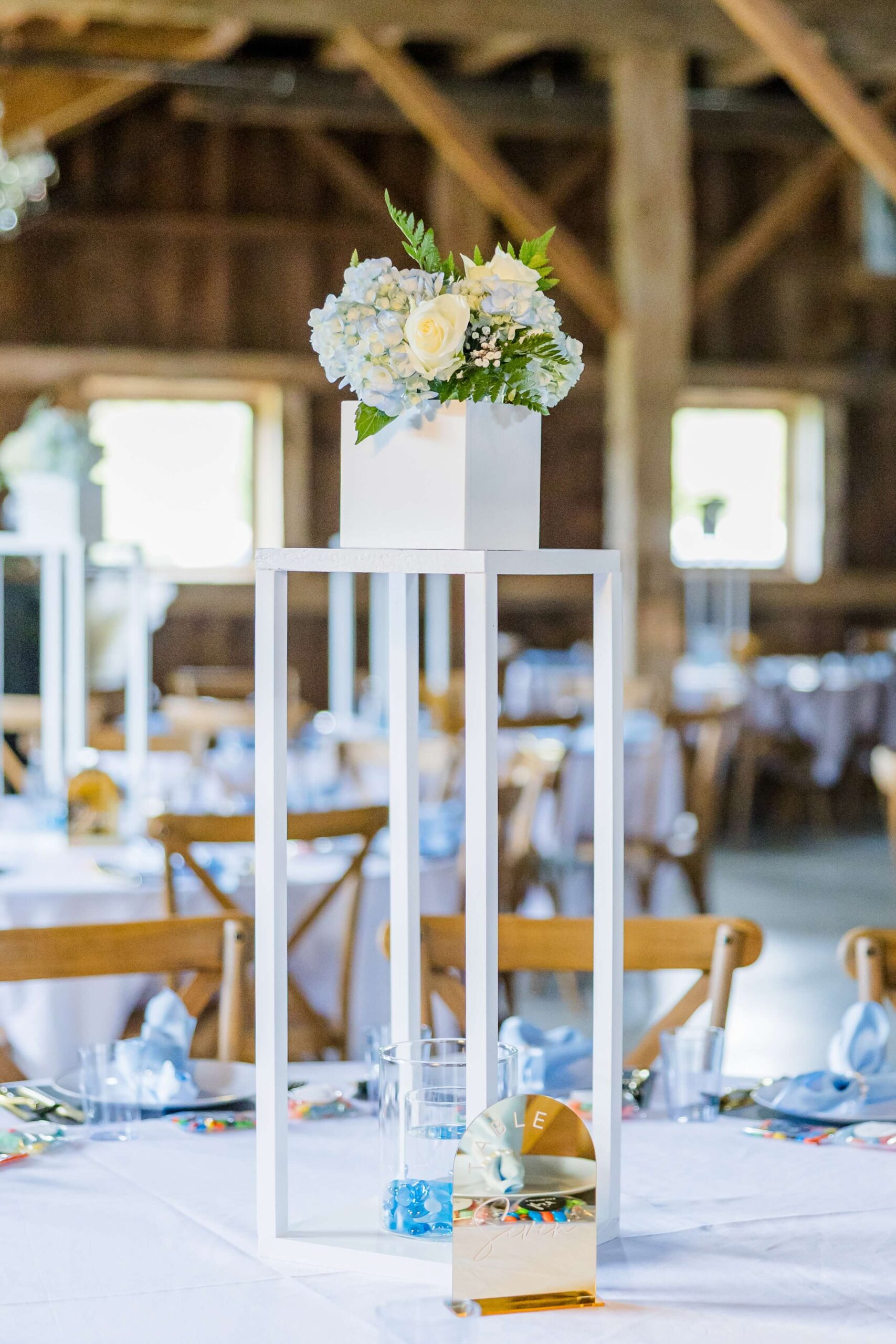 Details of a table setting with tall wooden towers and floral on top with blue napkins