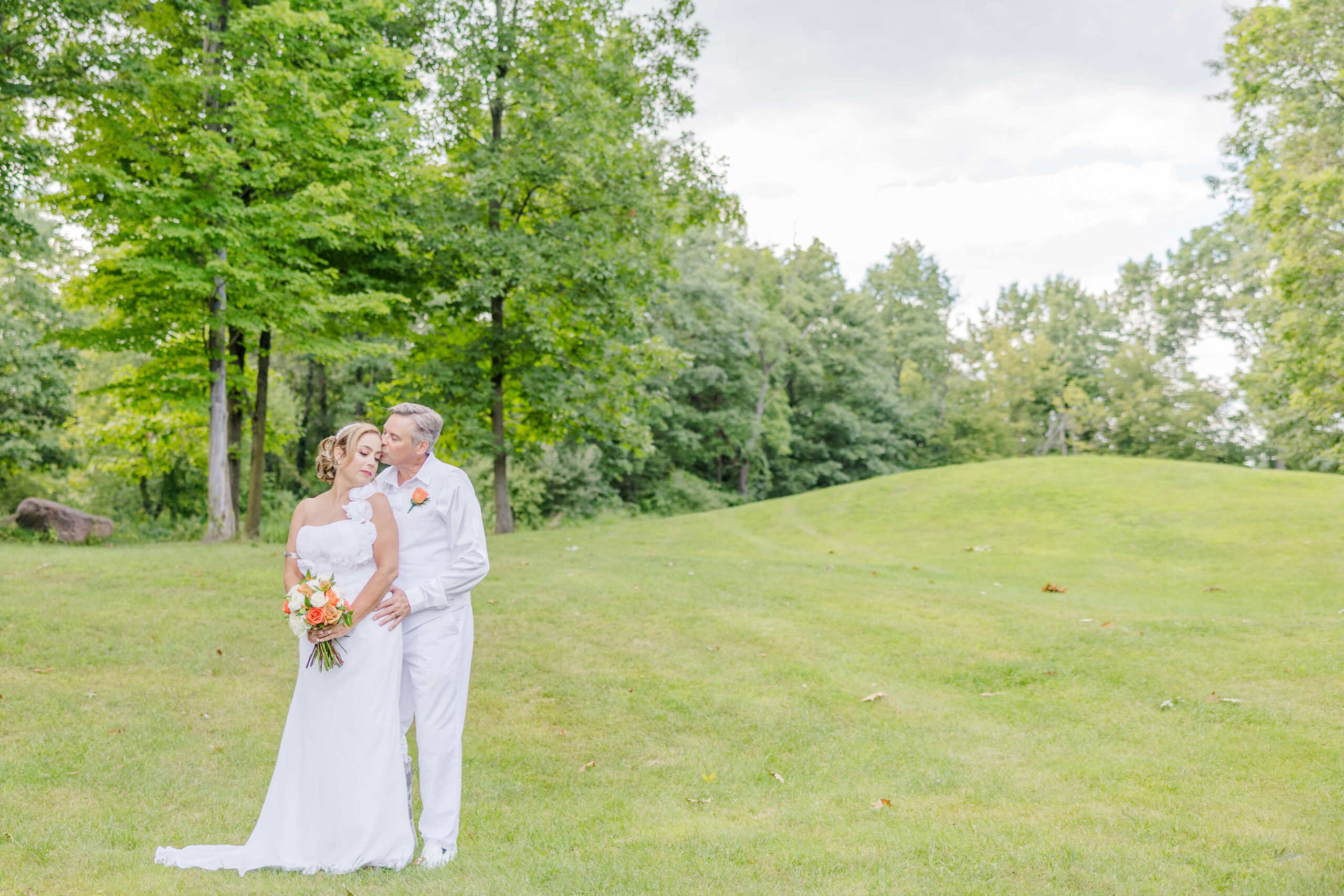 Newlyweds snuggle standing on a hill at one of the golf course wedding venues in michigan