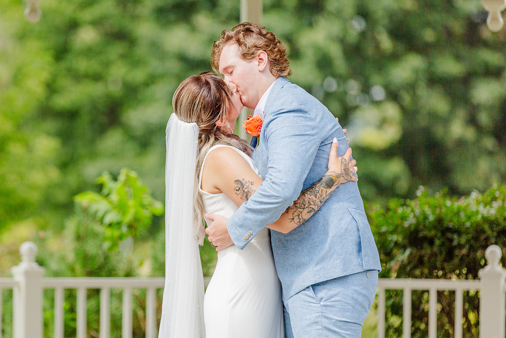 A bride and groom embrace for a kiss during their ceremony under a gazebo