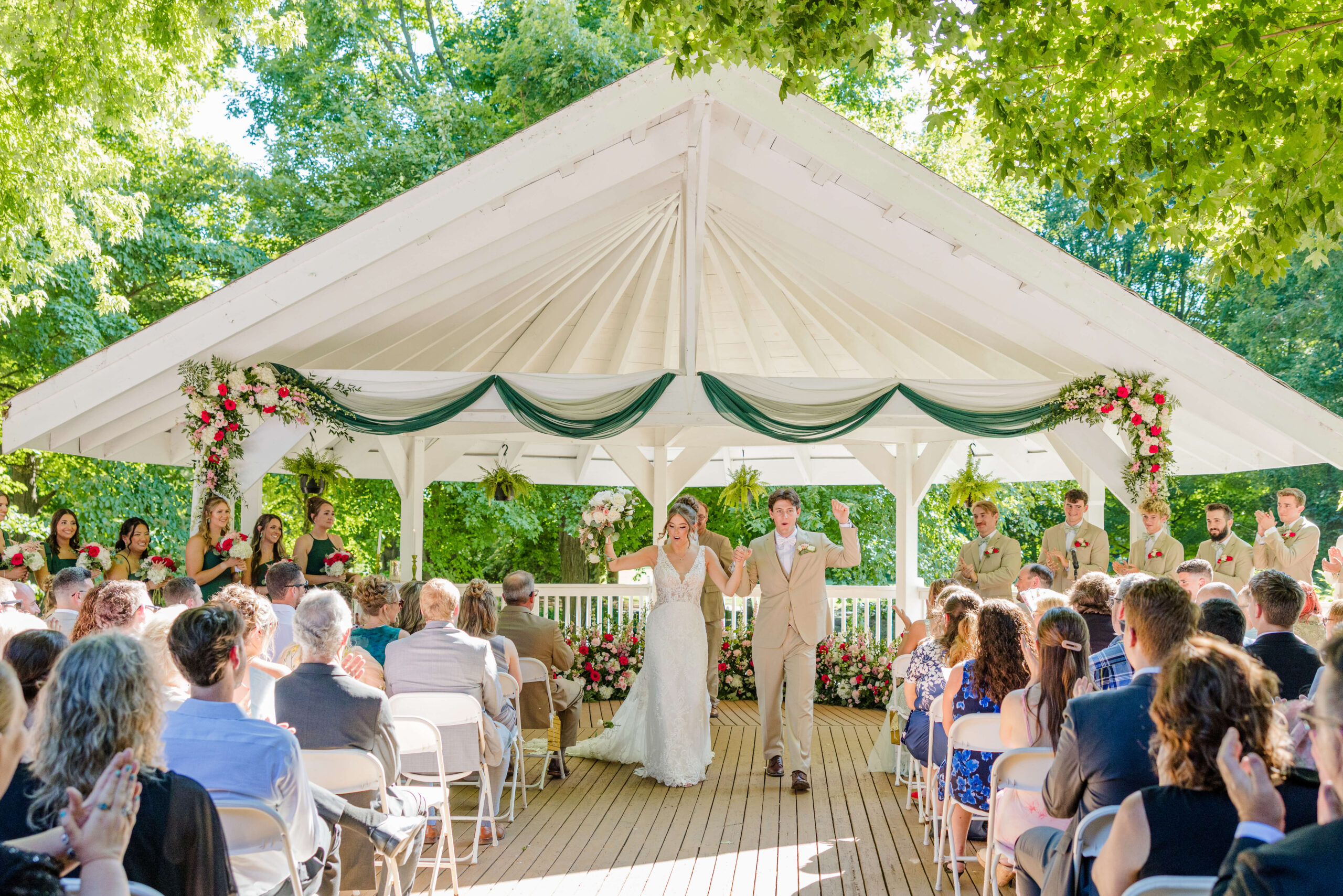 Newlyweds cheer while walking up the aisle of their outdoor golden hawk golf course wedding ceremony as guests clap