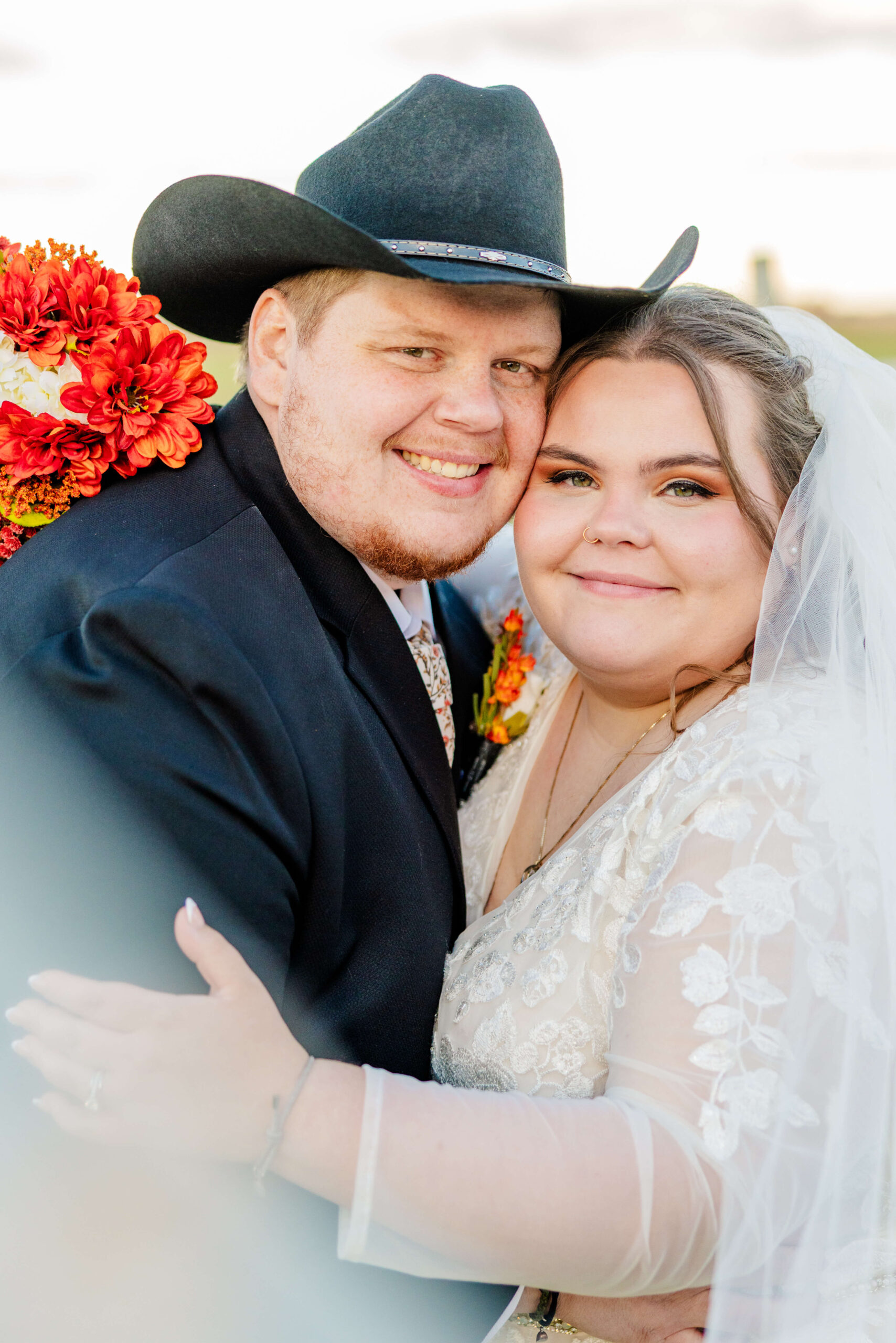 A happy couple snuggle cheek to cheek in a pasture at sunset during their sutton barn wedding