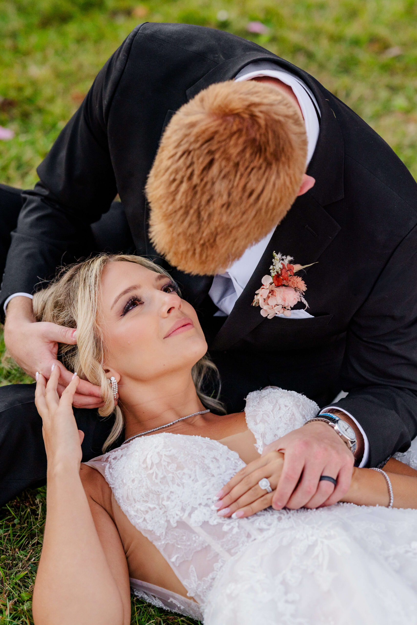 A bride rests her head in the lap of her groom as they snuggle in a lawn at their zingerman's cornman farms wedding