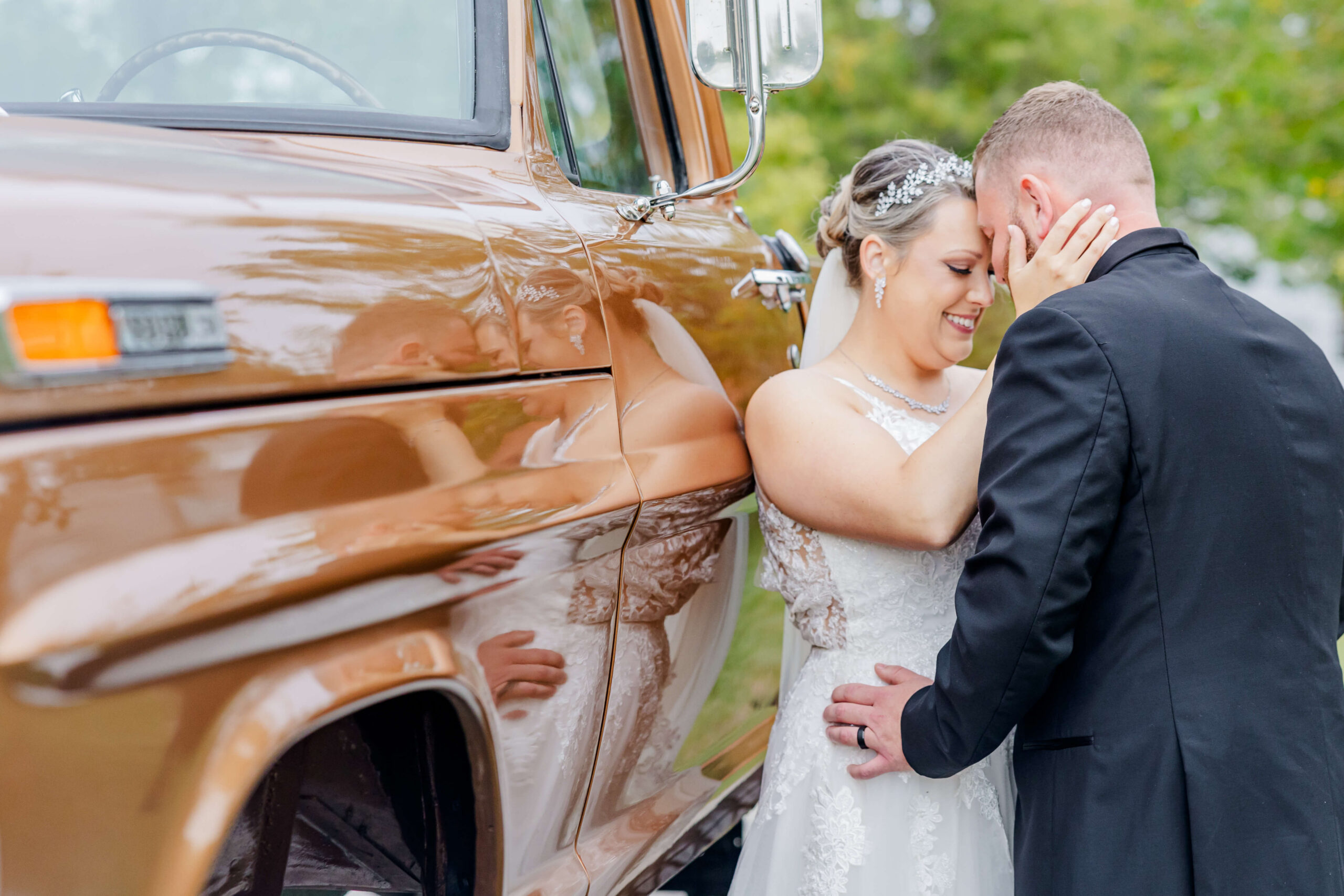 Newlyweds snuggle against a vintage lifted pickup truck
