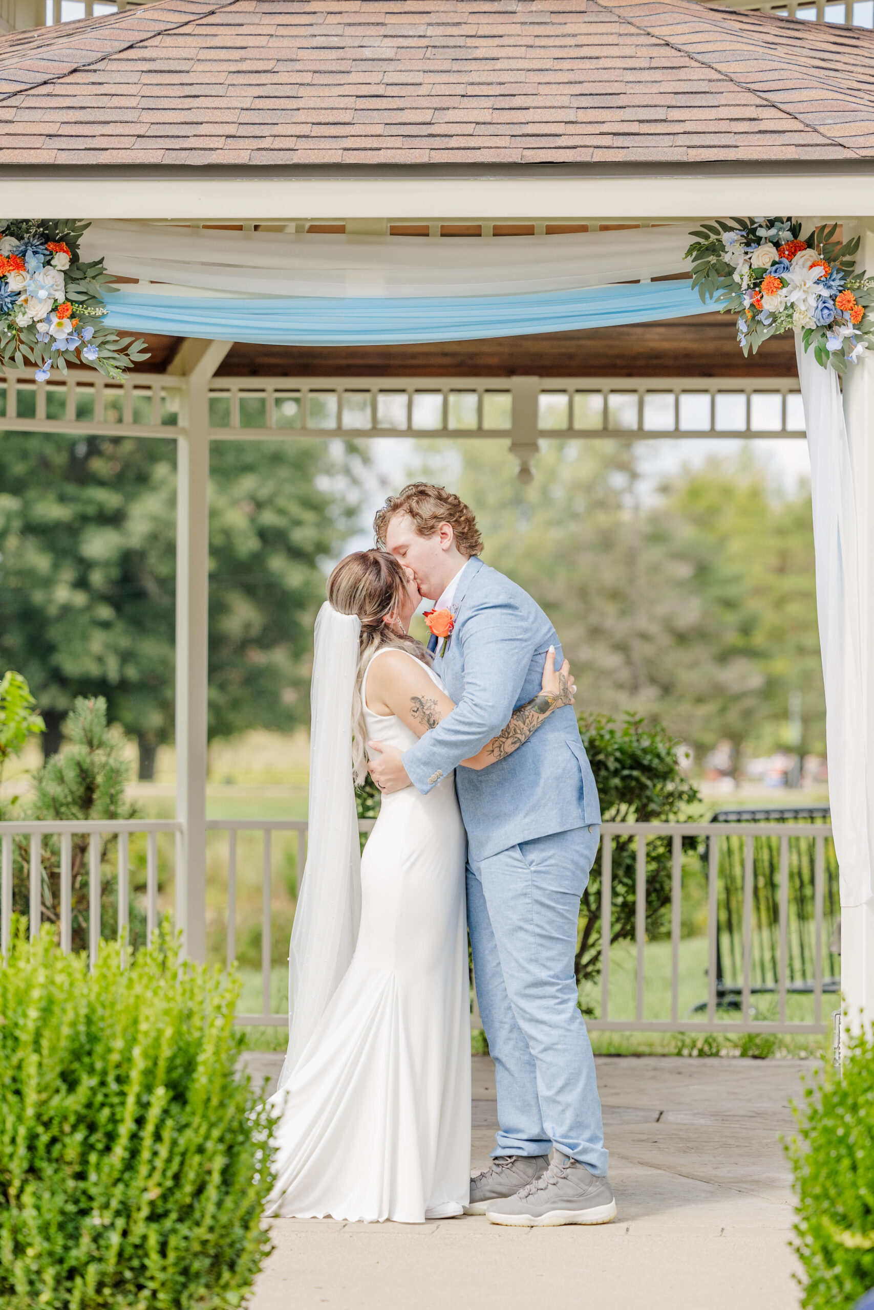Newlyweds kiss under a gazebo with a big embrace at one of the wedding venues in Rochester, MI