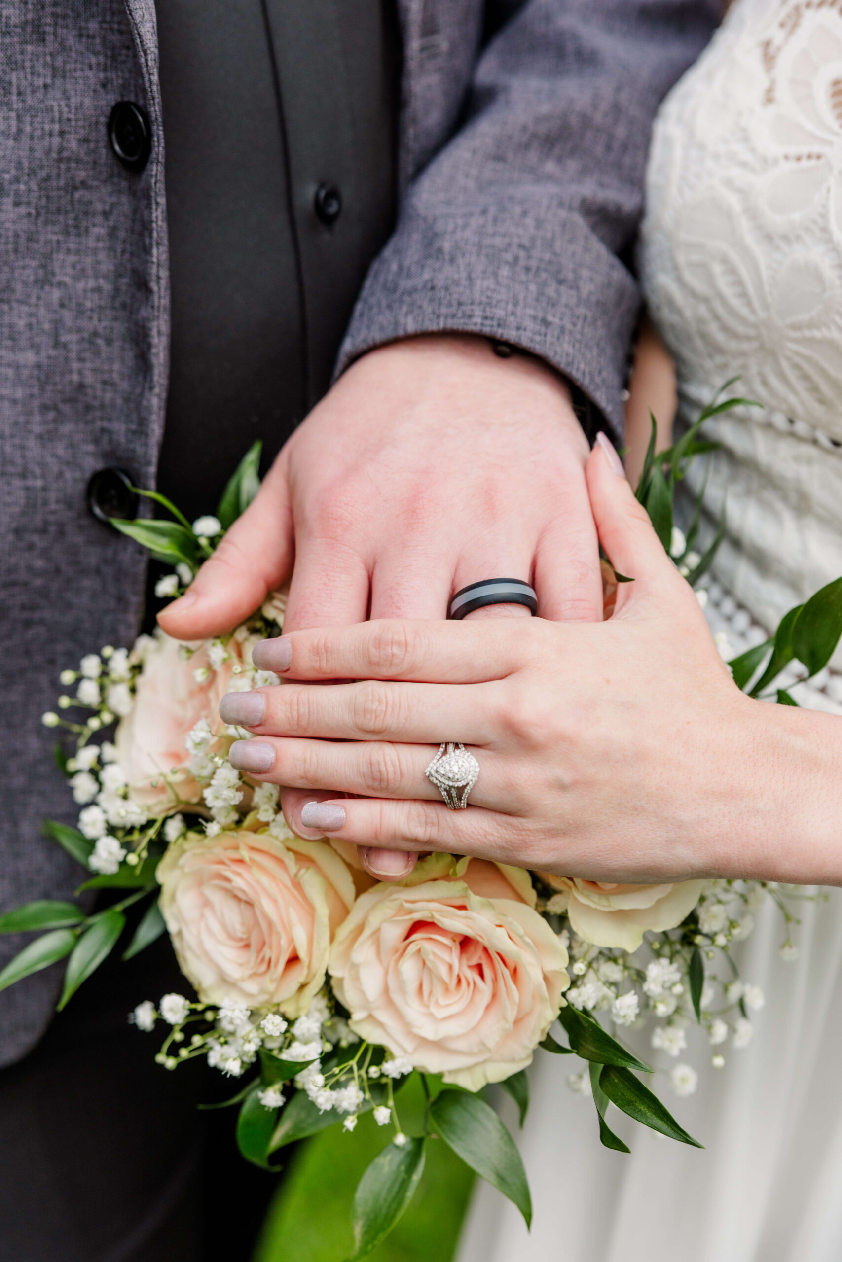 Details of the newlywed's hands over the bouquet with their ring hands