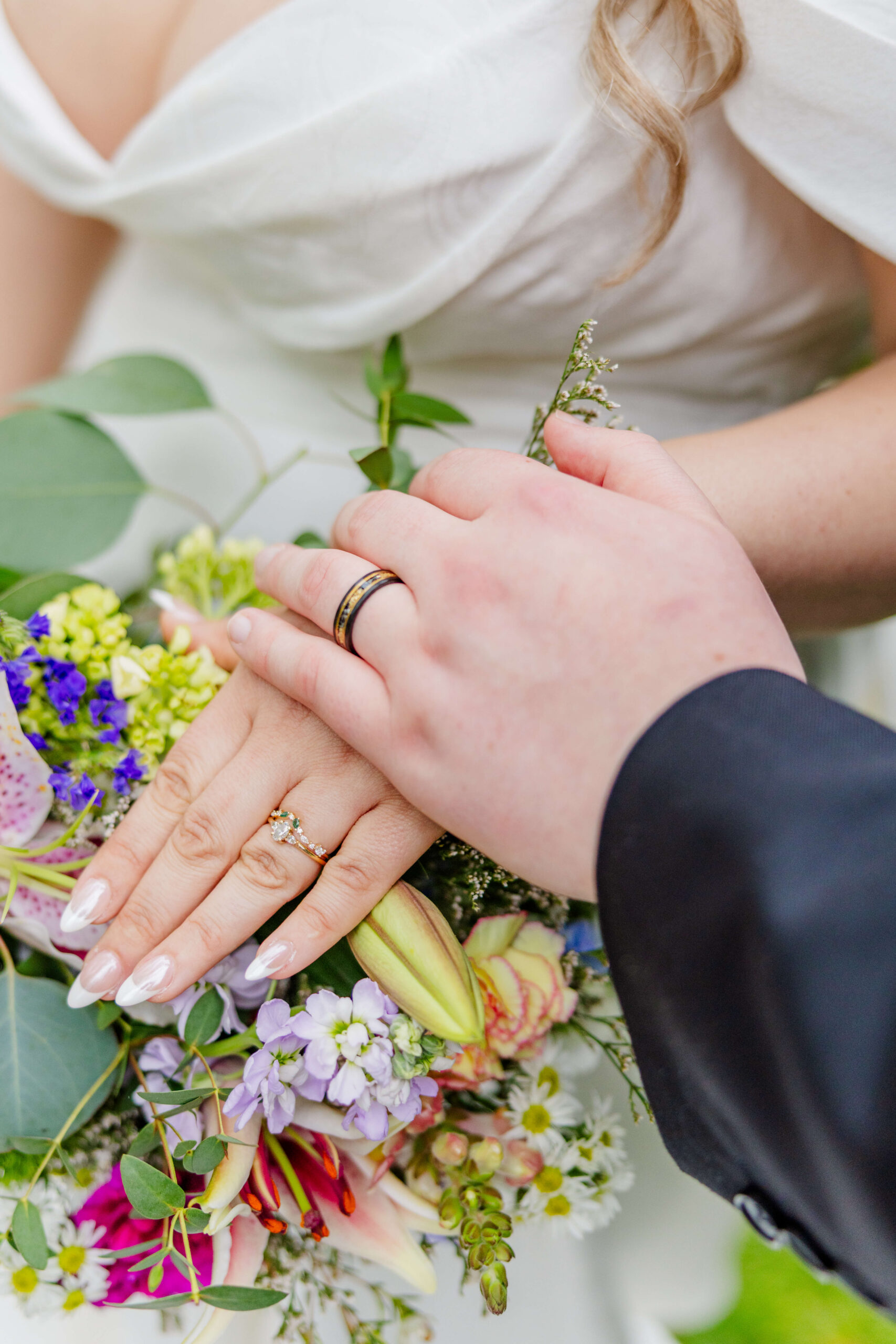 Details of a bride and groom's hands on a bouquet during their cherry creek golf club wedding