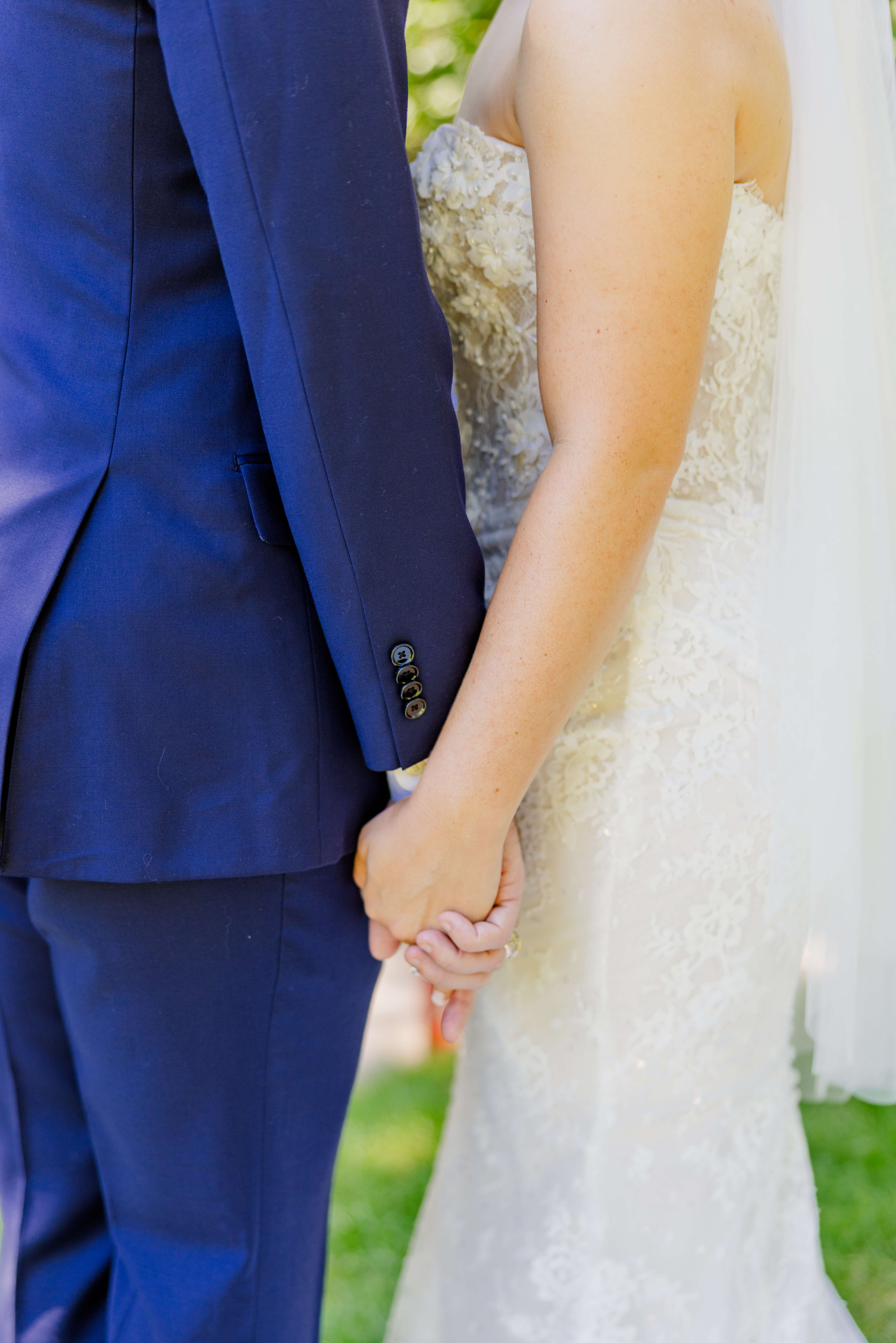 Details of the bride and groom holding hands at their side