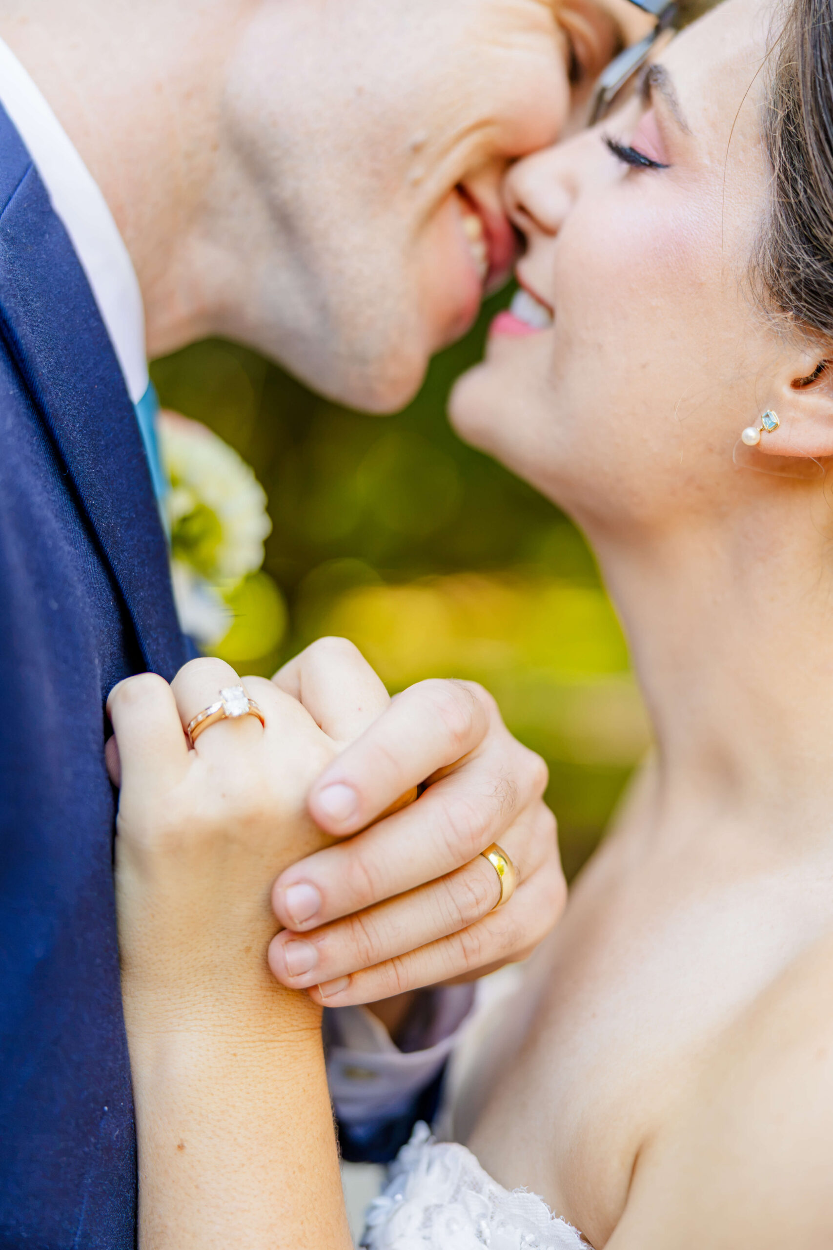 Newlyweds lean in for a kiss while holding hands agains groom's chest during their woodbridge event barn wedding