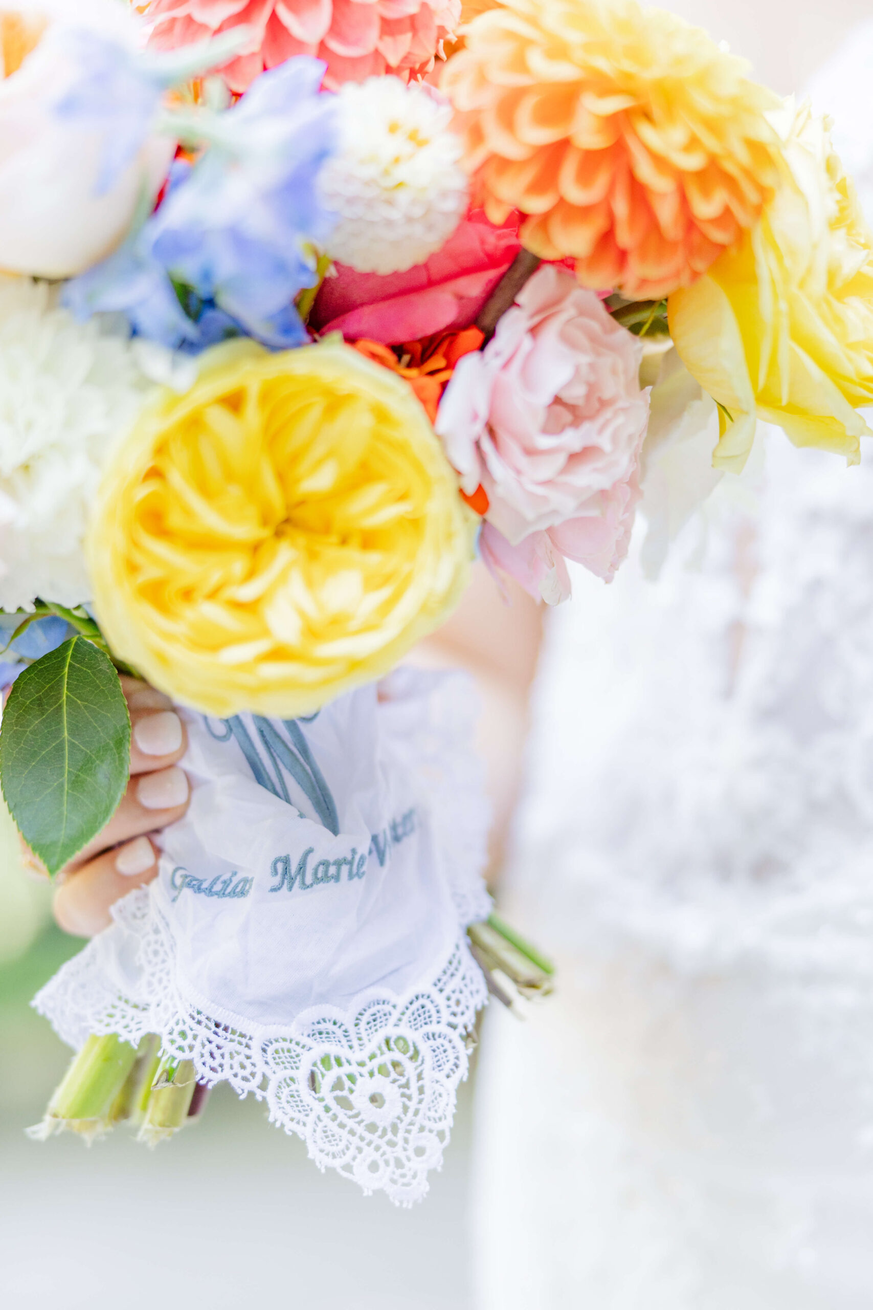 Details of a bride's colorful bouquet with a lace wrap in her hand